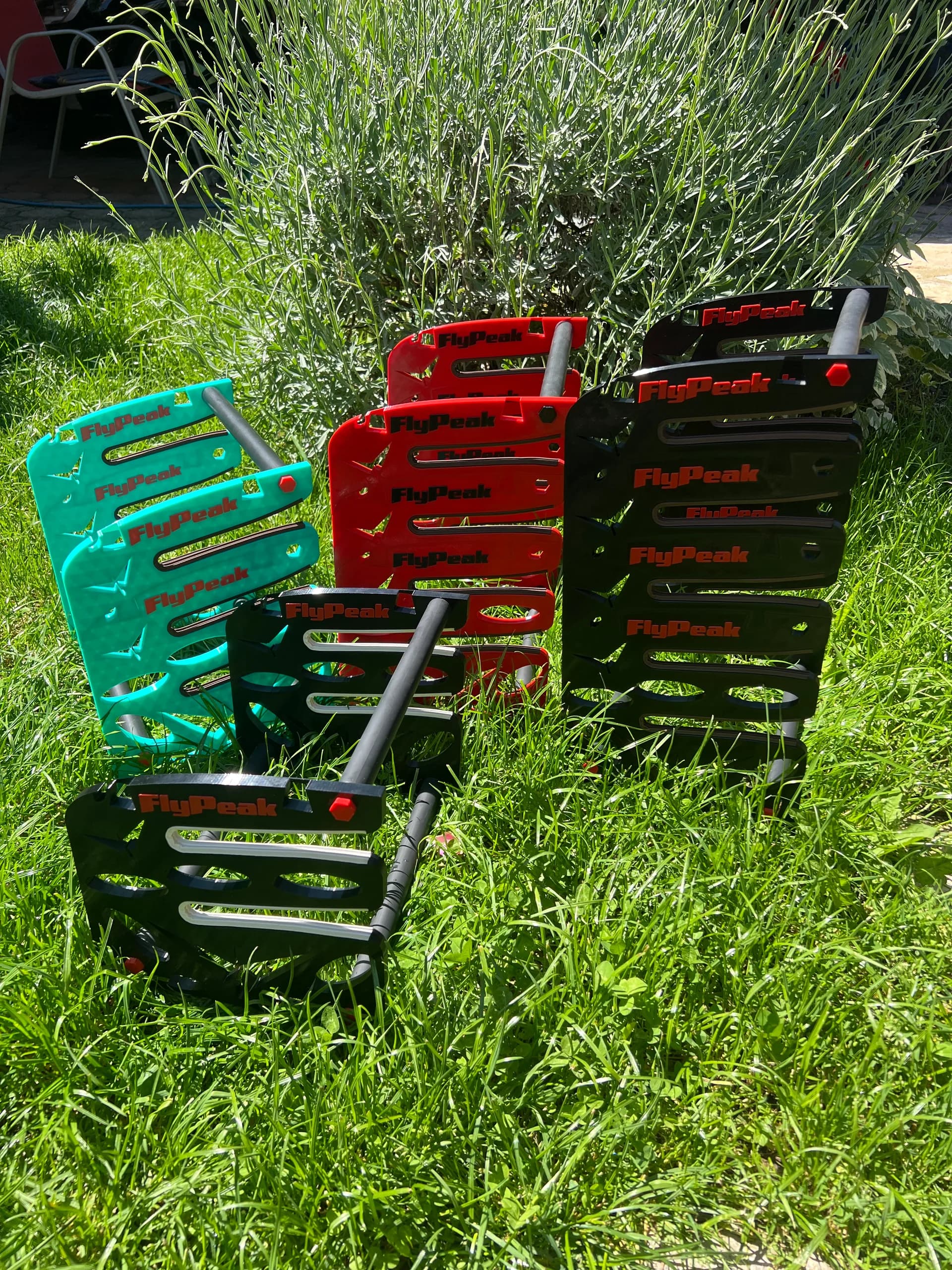 FlyPeak glider stands in turquoise, red and black on grass