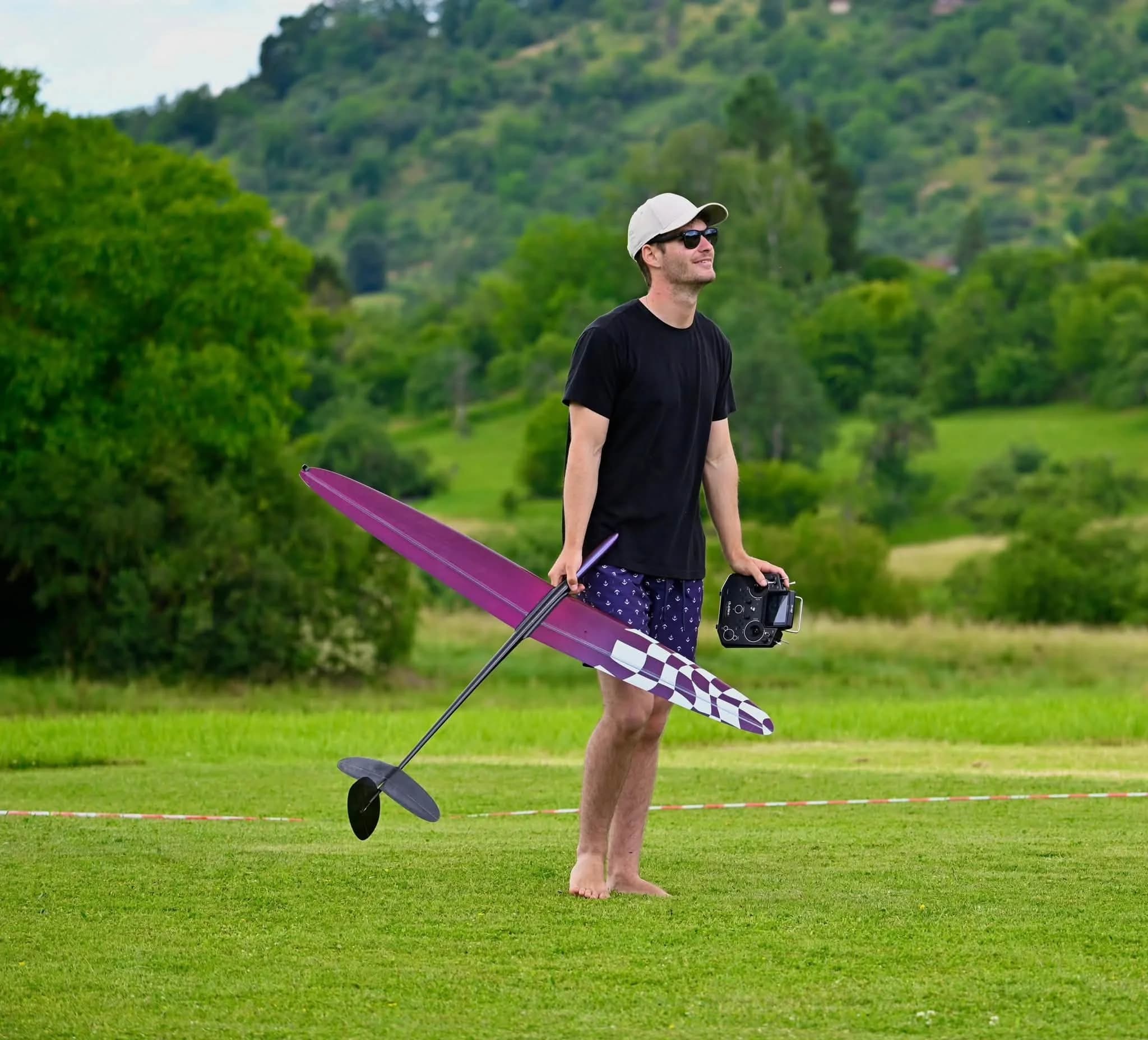 Lukas Dietrich holding a purple glider and radio transmitter on grass
